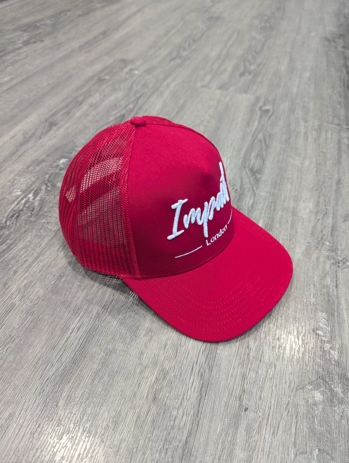 Red trucker cap with white logo from Impact London