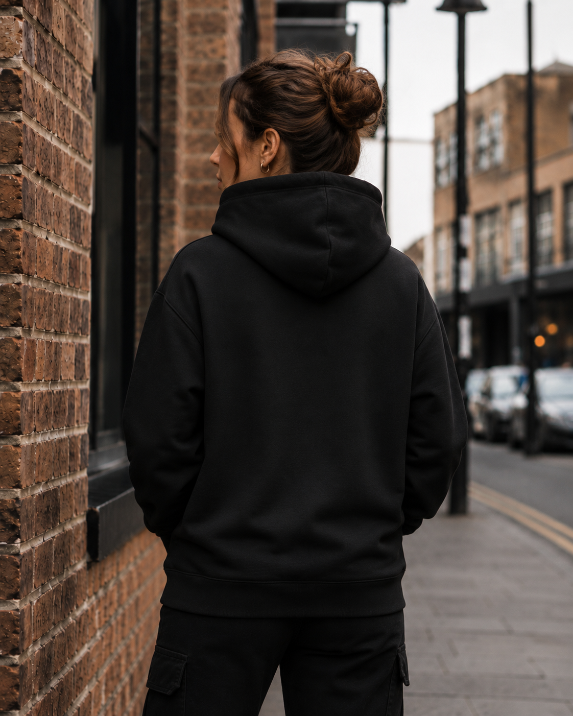 Female model wearing Impact London black hoodie with white embroidered logo from the back