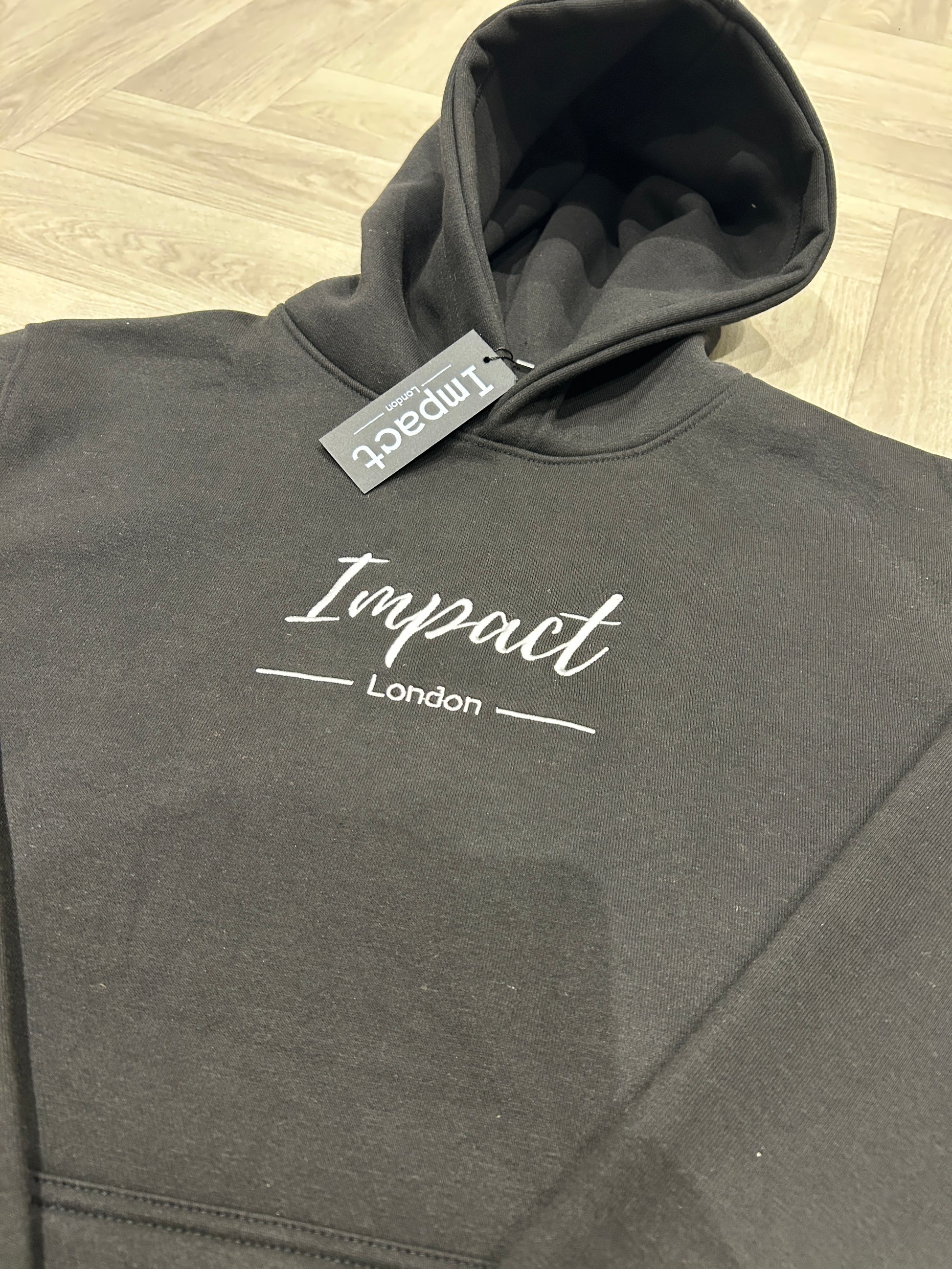 Close up of embroidered Impact London logo on black hoodie