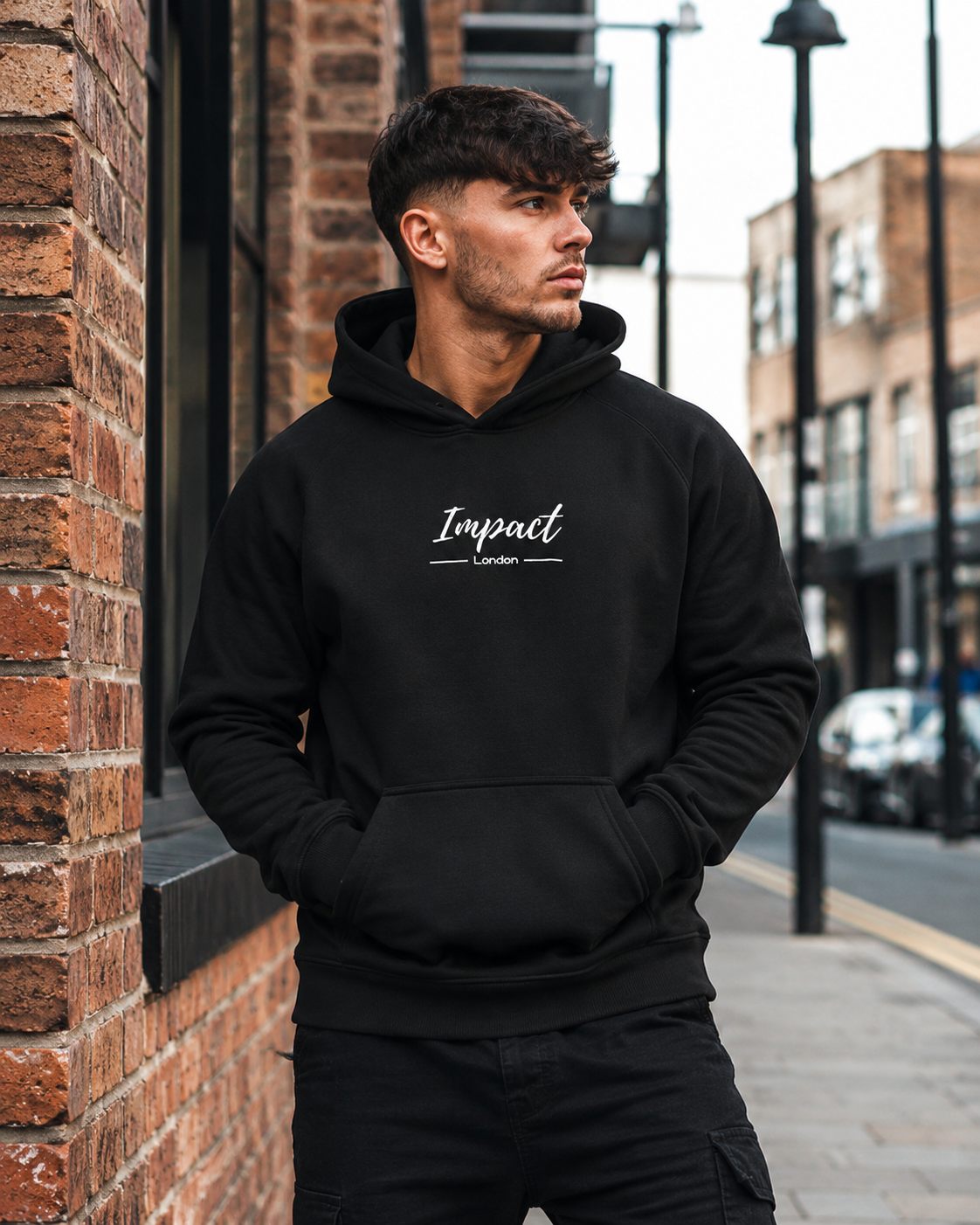 Male model wearing Impact London black hoodie with white embroidered logo