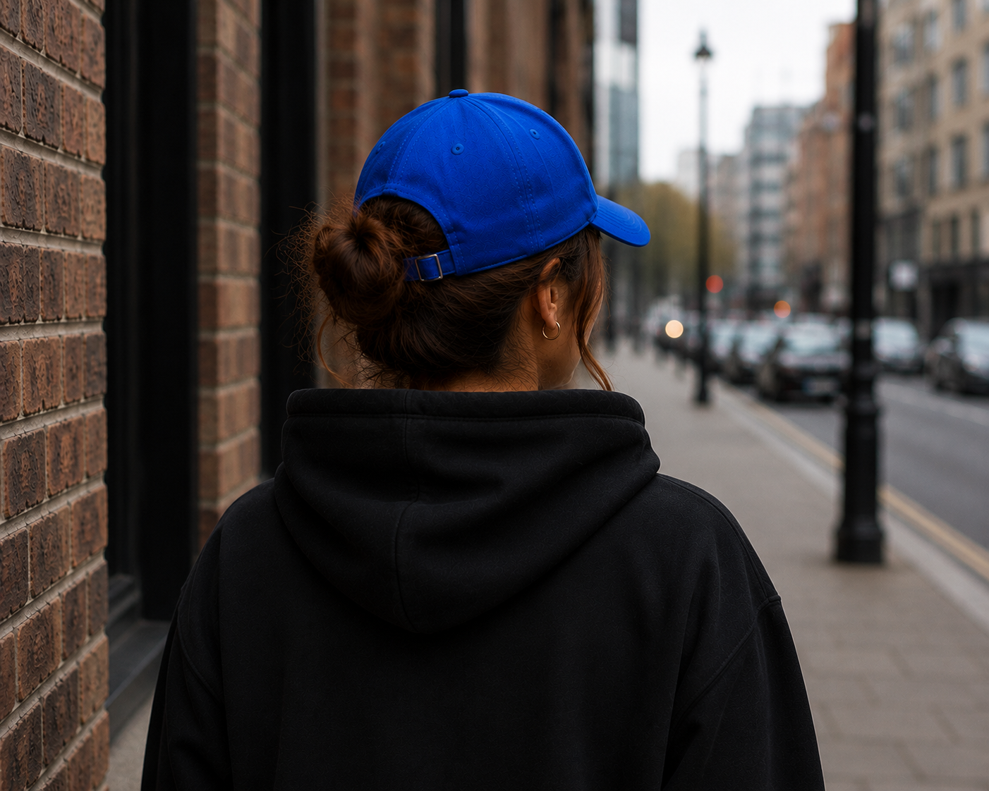 Female model wearing Impact Signature Royal Blue Cap with a view from the back by Impact London in an urban London setting