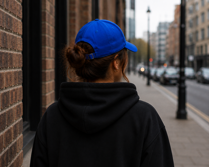 Female model wearing Impact Signature Royal Blue Cap with a view from the back by Impact London in an urban London setting