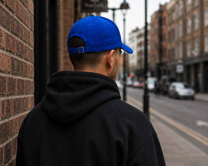 Male model wearing Impact Signature Royal Blue Cap with a view from the back by Impact London in an urban London setting