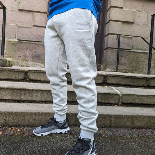 male model wearing light grey tracksuit bottoms with white logo and Nike react trainers